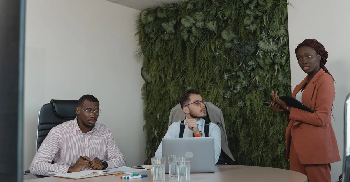 Une équipe diversifiée de professionnels participant à une réunion stratégique de bureau avec des plantes vertes en décoration.