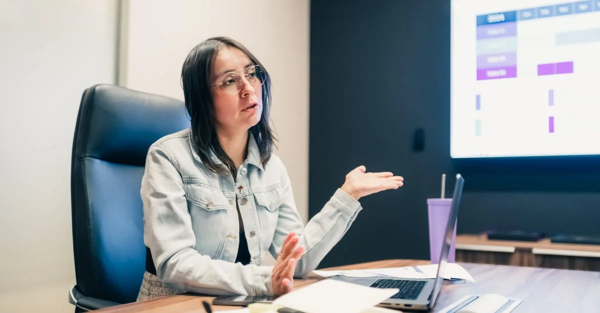 Femme d'affaires expliquant un concept lors d'une réunion avec une présentation affichée à l'écran.