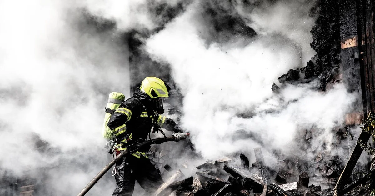 Un pompier déterminé combat un incendie féroce au milieu de la fumée épaisse, mettant en lumière le courage et la bravoure.