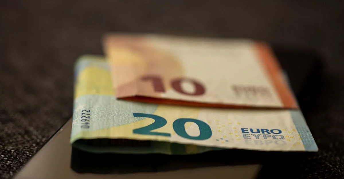 Un gros plan détaillé de billets de 10 et 20 euros placés sur un smartphone, représentant la finance et la technologie.