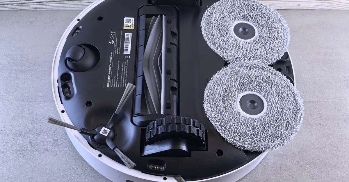 Vue détaillée du dessous d'un aspirateur robot montrant les brosses et les roues.