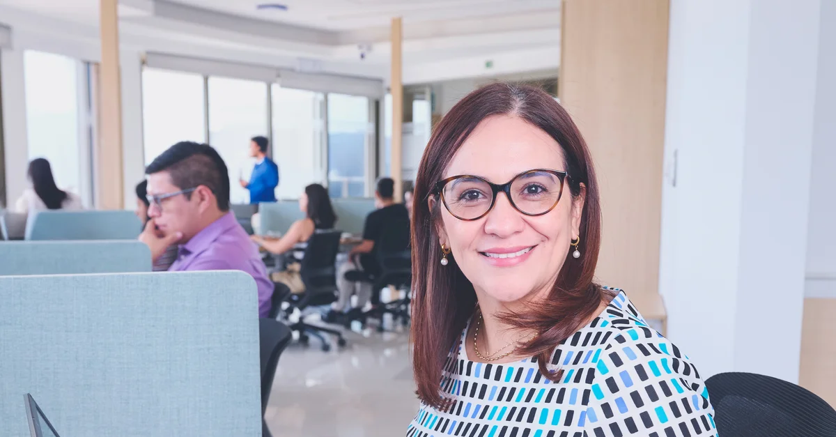 Femme confiante dans un bureau dynamique, mettant en valeur le travail d'équipe et la productivité.