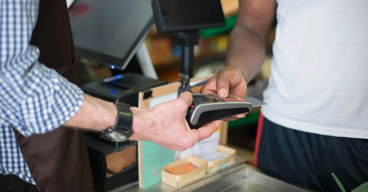 Un client effectuant un paiement avec une carte de crédit au comptoir de caisse d'un magasin en utilisant un lecteur de carte.
