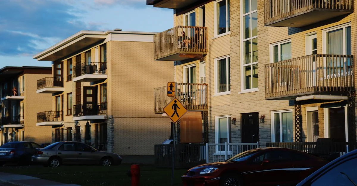 Charmants bâtiments résidentiels à Québec, capturés pendant une lueur vibrante au coucher du soleil, avec des voitures et des paysages urbains.