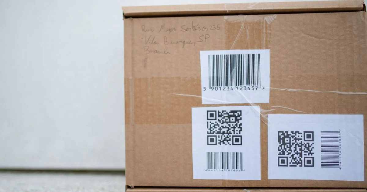 Gros plan d'un colis en carton avec des codes QR et un code-barres, idéal pour des concepts de livraison et d'expédition.